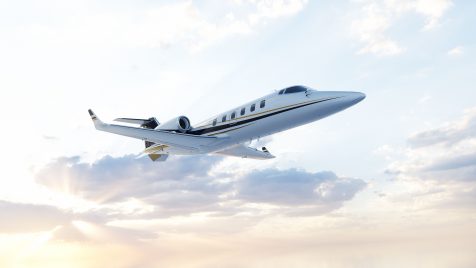 Jet Charter A sleek private jet flies through a partly cloudy sky, with sunlight illuminating the clouds and reflecting off the airplane's fuselage. Jetvia