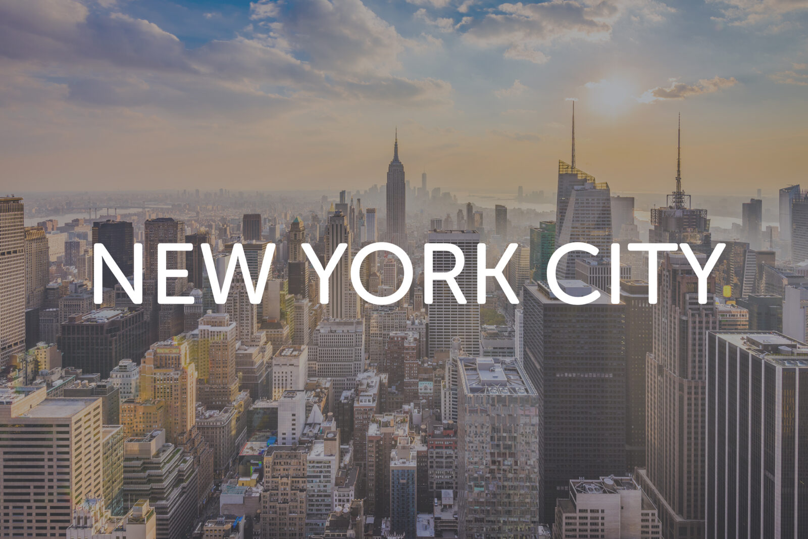 Jet Charter A cityscape of New York City at sunset with tall buildings and skyscrapers, including the Empire State Building, with the words "NEW YORK CITY" written across the image—perfect for anyone dreaming of skyscrapers or searching for flights from New York to Los Angeles. Jetvia